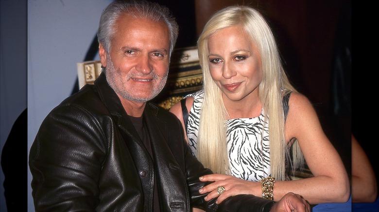 Gianni Versace con una chaqueta de cuero negra sentado junto a su hermana Donatella con un top blanco y negro alrededor de 1996.
