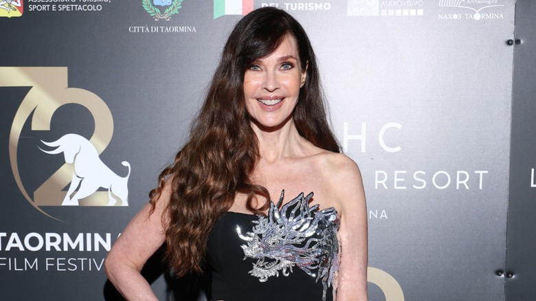 Carol Alt posa con un vestido negro sin tirantes con adornos plateados junto con su largo cabello castaño suelto en rizos sueltos mientras asiste al 72º Festival de Cine de Taormina en Italia en 2026.