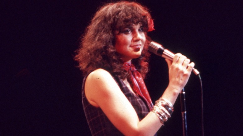 Linda Ronstadt en la década de 1970 actuando en el escenario con un pañuelo alrededor del cuello.