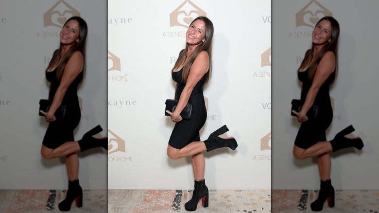 Soleil Moon Frye posando con el pie levantado con un vestido negro con botas de plataforma negras.