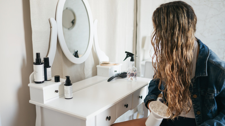 Una mujer usando un secador de pelo en sus rizos.