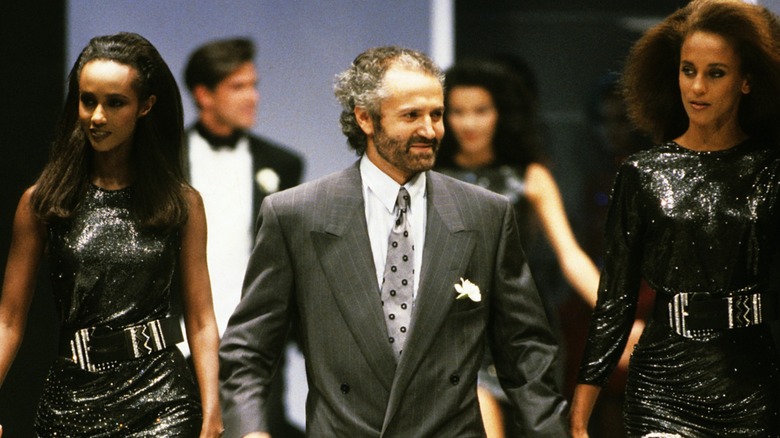 Gianni Versace presentando su colección en 1987 junto a dos modelos