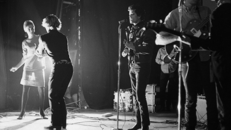 The Velvet Underground actuando en el escenario con Edie Sedgwick y Gerard Malanga bailando.