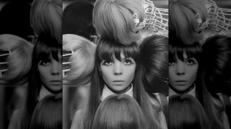 La modelo Penelope Tree durante una sesión de fotos editorial rodeada de pelucas en blanco y negro