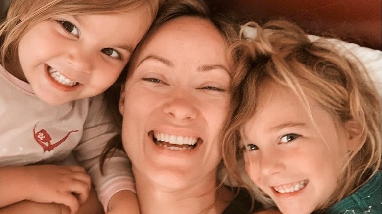 Olivia Wilde con sus dos hijos sonriendo en la cama en 2019.