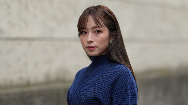 Una mujer con flequillo de cortina morena y cabello largo y liso.