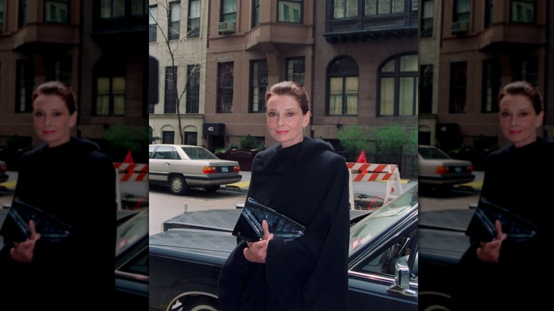 Audrey Hepburn en la calle de la ciudad de Nueva York durante el día con un abrigo negro.