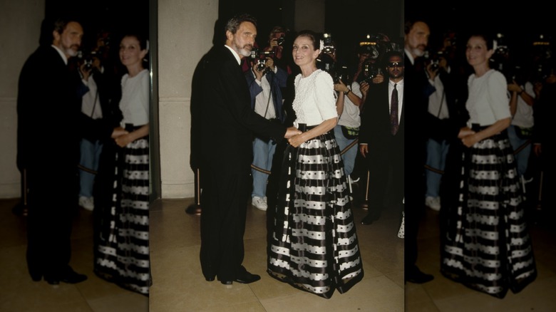 Audrey Hepburn en un evento con un top blanco y una falda amplia de rayas negras y plateadas.