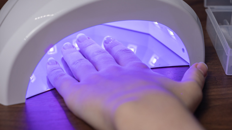 Una mano debajo de una lámpara de curado LED