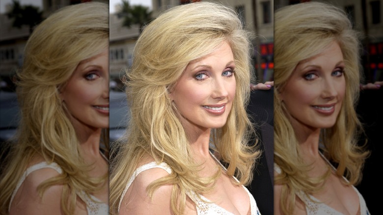 Morgan Fairchild en 2023 con el pelo ligeramente emplumado y un vestido blanco.