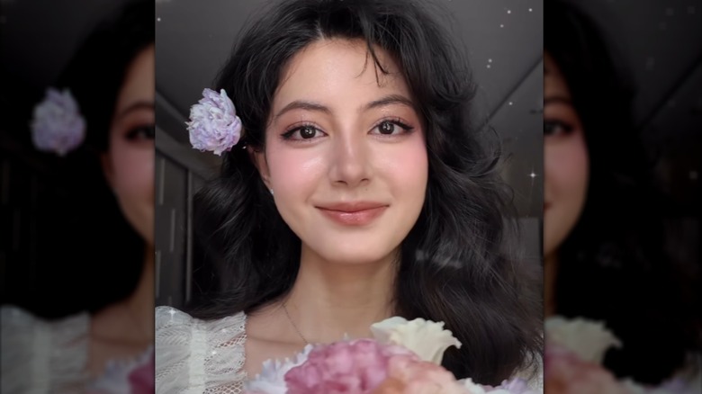 Una persona con un maquillaje cottagecore inspirado en flores se ve sonriendo.