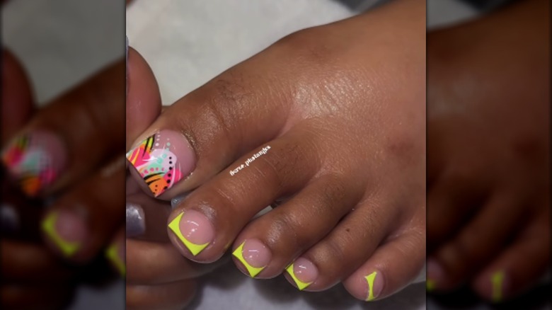 Una pedicura con puntas francesas neón y un diseño multicolor de los 90