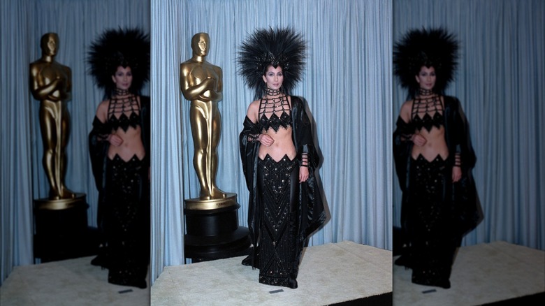 Cher lleva un conjunto negro brillante de dos piezas y un tocado de plumas en los Premios de la Academia de 1986.