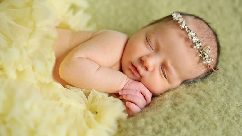 Bebé durmiendo con una corona de flores.