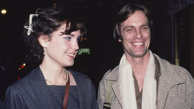 Elizabeth McGovern mira a Keith Carradine con el pelo rapado y con flequillo