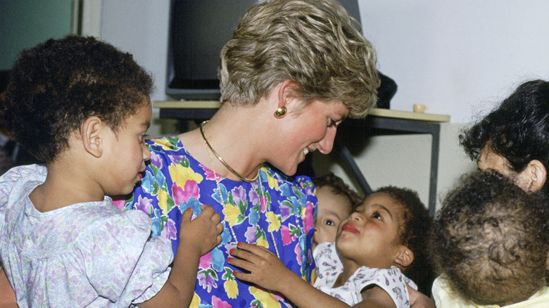 La princesa Diana con un colorido vestido floral abrazando a niños en Brasil.