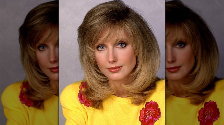 Morgan Fairchild en un retrato de 1990 con un suéter amarillo con detalles florales rojos.