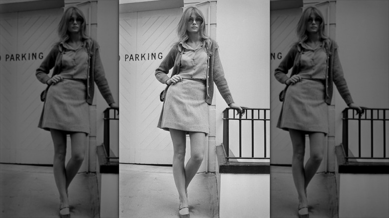 Jean Shrimpton posa con la mano en la cadera luciendo una falda corta y grandes gafas de sol.