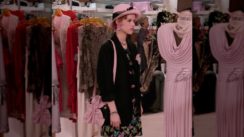 Molly Ringwald fotografiada como Andie Walsh con una chaqueta negra, un vestido floral y un sombrero rosa en Pretty in Pink.