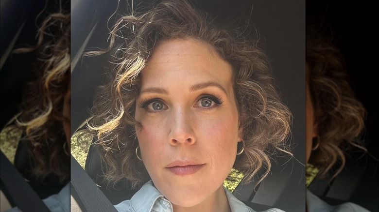 Erin Krakow aparece en una selfie de primer plano con cabello corto y rizado y un maquillaje suave y glamoroso.