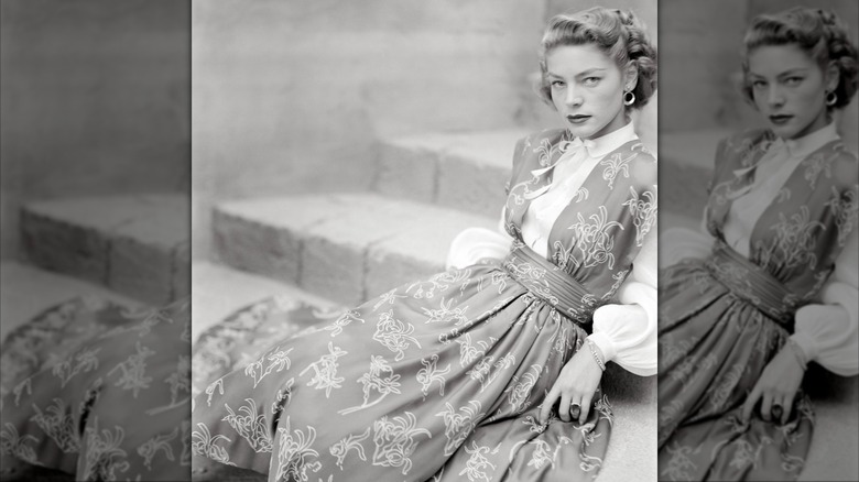 Lauren Bacall descansando en las escaleras con una blusa blanca y un delantal con estampado floral para la revista Glamour en agosto de 1949.
