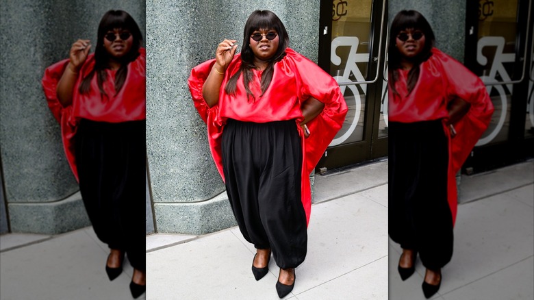 Gabourey Sidibe con camisa roja y pantalón negro.