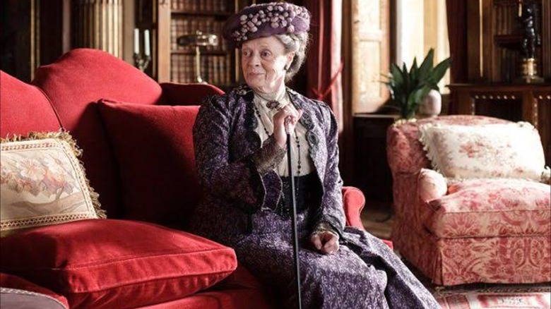 Maggie Smith como Violet Crawley con un traje morado de estilo victoriano en Downton Abbey
