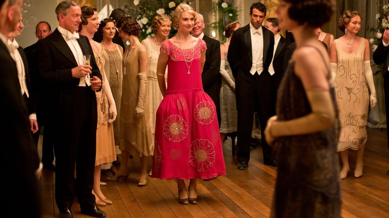 Lily James como Lady Rose con un vestido rosa brillante con cintura caída y adornos florales.