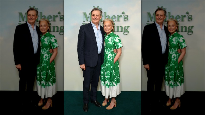 John Micklethwait (izq.) con traje junto a Kristin Scott Thomas (der.) con vestido verde floral