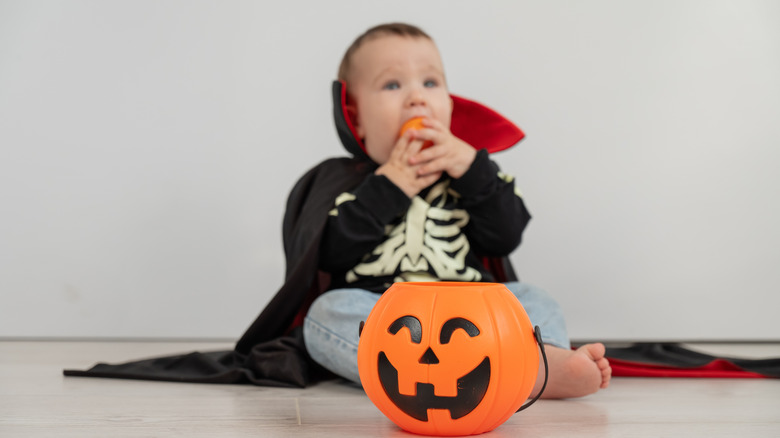 Un bebé disfrazado de vampiro y decoración de calabaza.