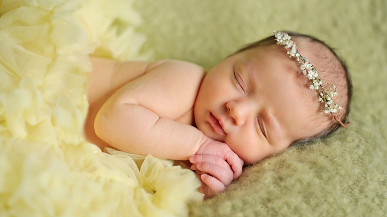 Un bebé durmiendo con una diadema de flores.