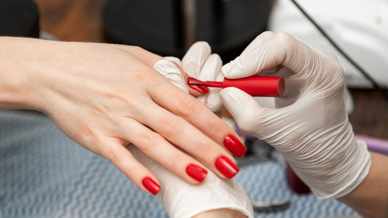 Una mujer a la que le pintan las uñas de rojo.
