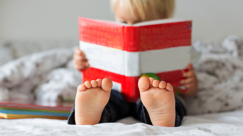 Una foto muestra a un niño desenfocado mientras lee un libro con rayas rojas y blancas.