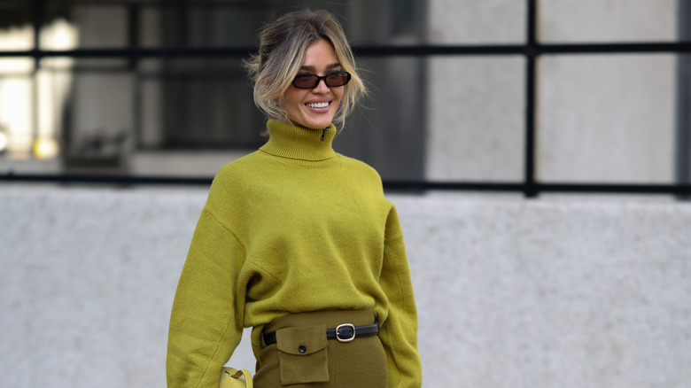 Una mujer posando con un suéter verde chartreuse