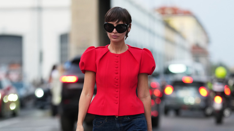 Una mujer vestida con una blusa roja con mangas abullonadas.